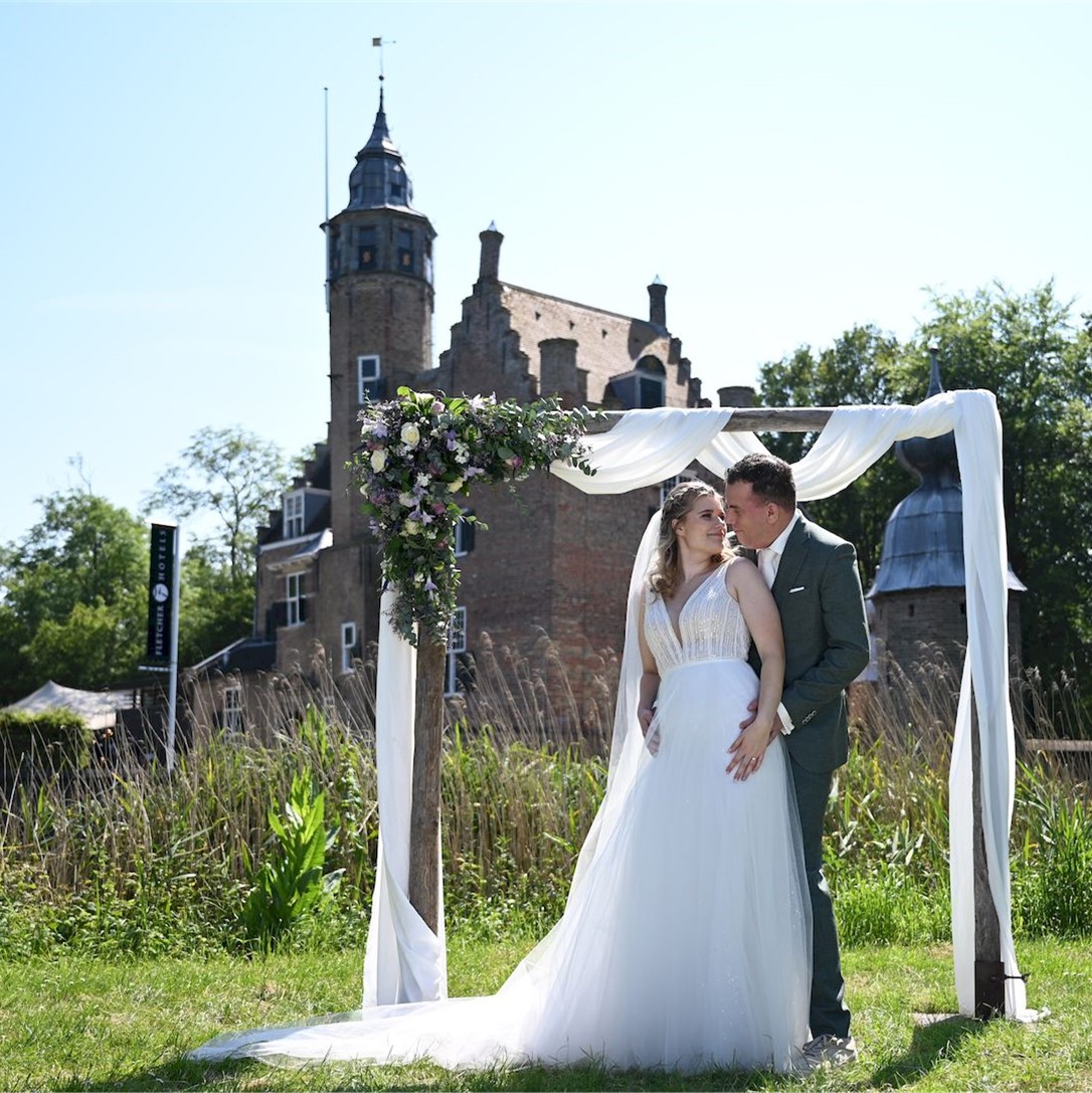 Een bruid en bruidegom in trouwkleding voor een kasteel, foto gemaakt door Deesjavu Fotografie