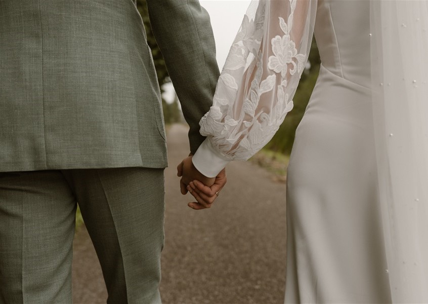Couple holding hands on pathway.