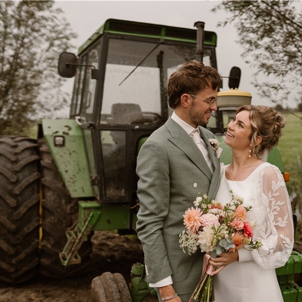 Couple smiling near a tractor.